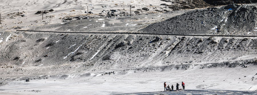 A group of people in the distance stand in relief to the rock and sand cliff face in the distance