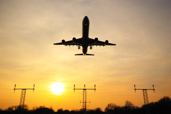 An airplane at sunset landing at an airport.