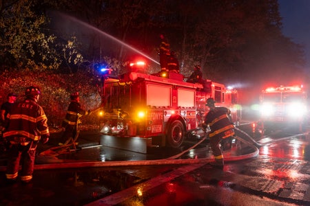 Firefighters surrounding their truck on an urban street at night
