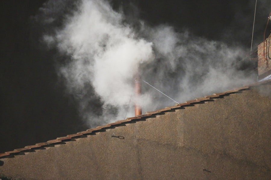 White smoke billows from red pipe on rooftop