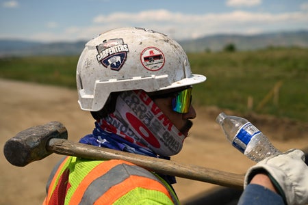 Close up view of a construction worker in profile drinking water during high 90-degree temperatures