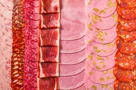 Cold cuts meat charcuterie slices in a row, pepperoni, chopped, ham, prosciutto and chorizo
