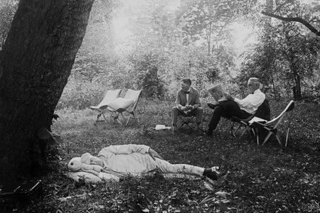 Thomas Edison sleeping under a tree in a light-colored suit.