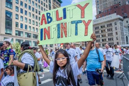 Young girl holds sign that reads "Ability Infinity" at 2019 Disability Pride Parade in New York City.