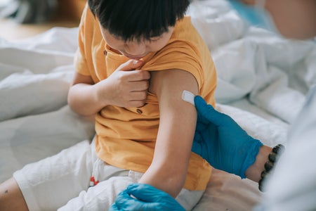 Doctor applying bandage to child's arm after a vaccine injection