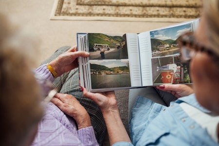 A high angle view of two unrecognisable mature women looking through a photo album as they sit on a sofa at home