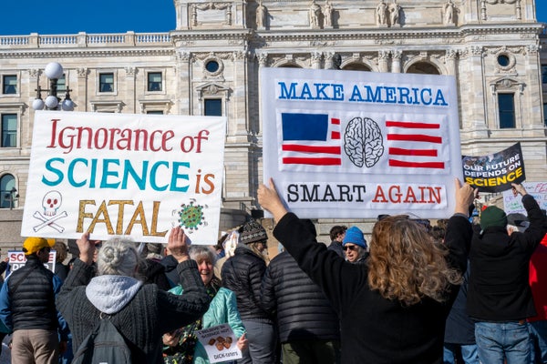 Protesters display signs reading "ignorance of science is fatal" and "make America smart again"