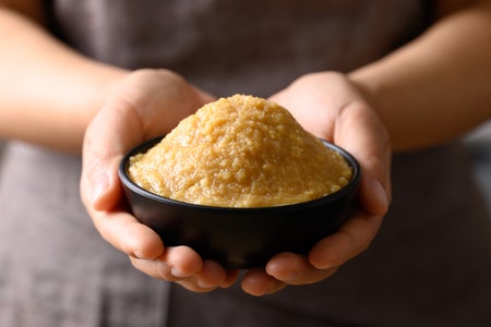 Hands holding miso paste in a black bowl