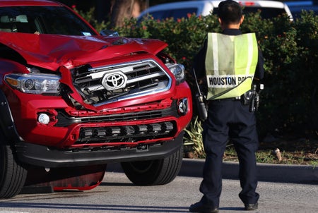 Houston Police officer investigating a scene where a pedestrian was killed after being struck by a motorist driving a pickup truck on Westheimer Road, near Hayes Road Wednesday, July 19, 2017, in Houston. The police officer is wearing a safety vest, standing in the street in front of the damaged red colored Toyota pickup