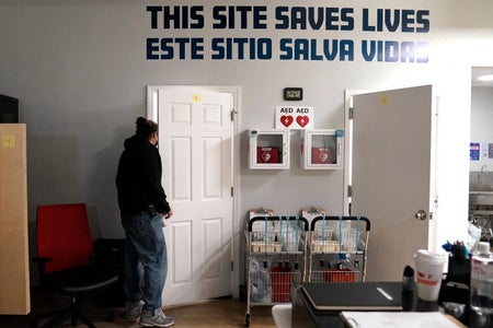 A worker looks through a slightly opened door to check on a patient at an overdose prevention center in New York City on February 8, 2022. "This site saves lives," reads an inscription on the wall