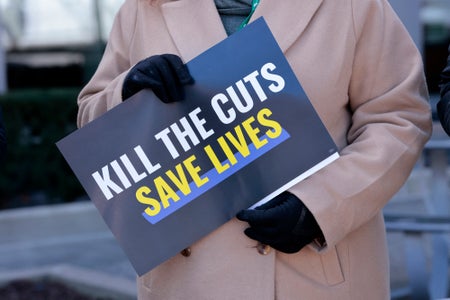 Person holding "Kill the Cuts" sign