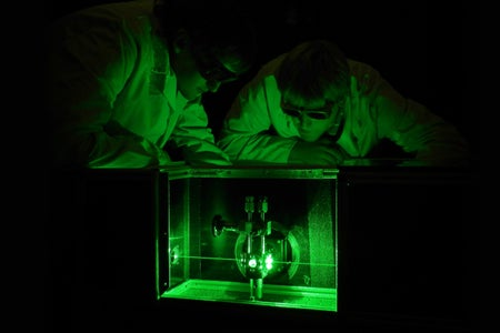 Two researchers observe above a Laser Raman system for the analysis of the tritium gas composition in the WGTS