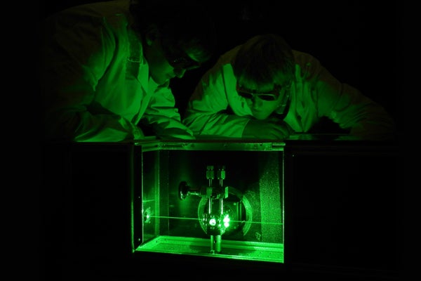 Two researchers observe above a Laser Raman system for the analysis of the tritium gas composition in the WGTS