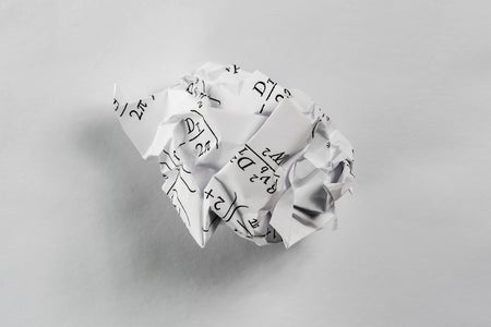 Paper with math equations crumpled up into a ball and discarded on white surface