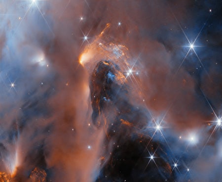 Glowing orange gas clouds with scattered bright newborn stars