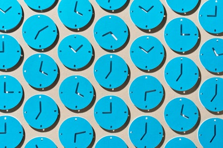 Conceptual photo illustration of many blue clocks showing different times made from paper cutouts laid out in a pattern