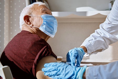Healthcare worker using syringe to administer a vaccine injection into an older patient's arm