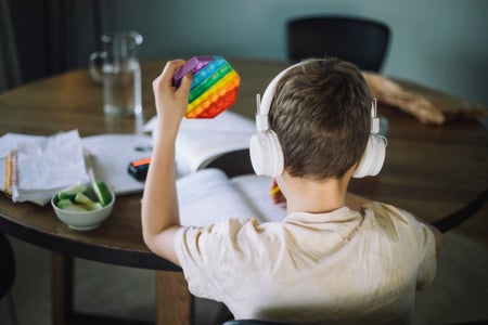 Rear view of boy with white headphones and a rainbow colored toy.