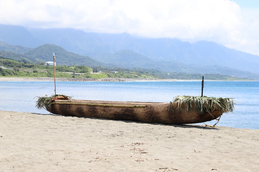 Wooden canoe on a white beach with the ocean in the background